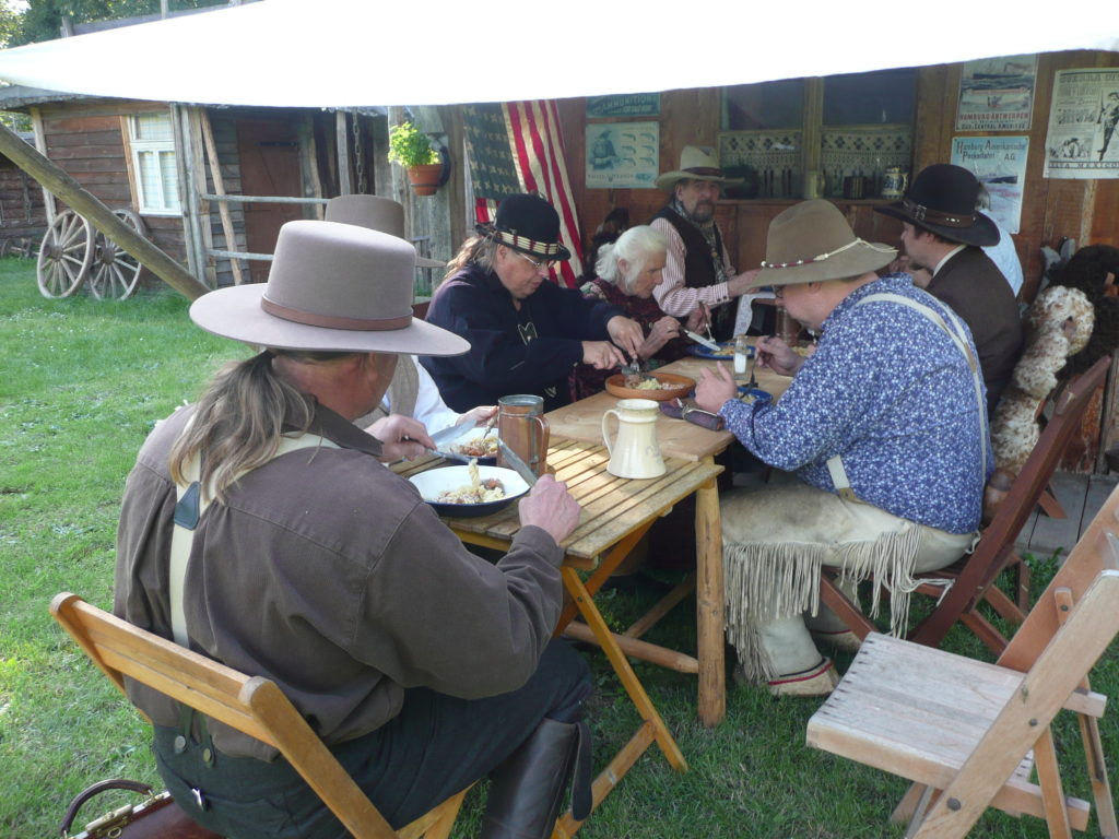 Authentic Camp 2021 - Cowboys dining in front of a bunkhouse