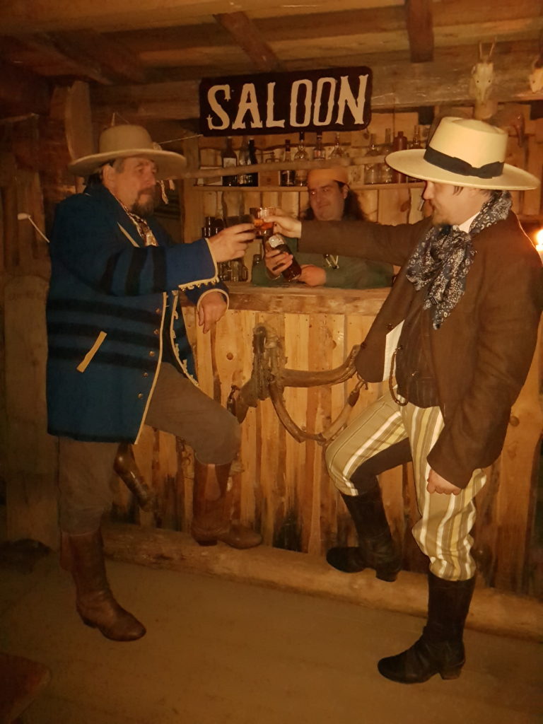 Authentic Camp 2021 - Two Cowboys toasting with whiskey in saloon